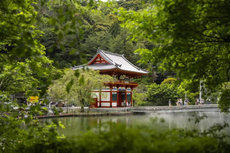 traditional japanese temple by a lake surrounded by lush green trees